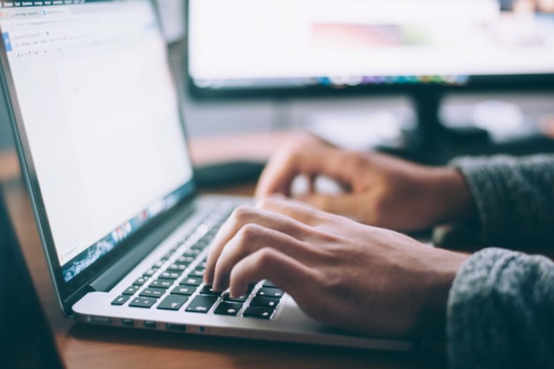 man typing on silver laptop